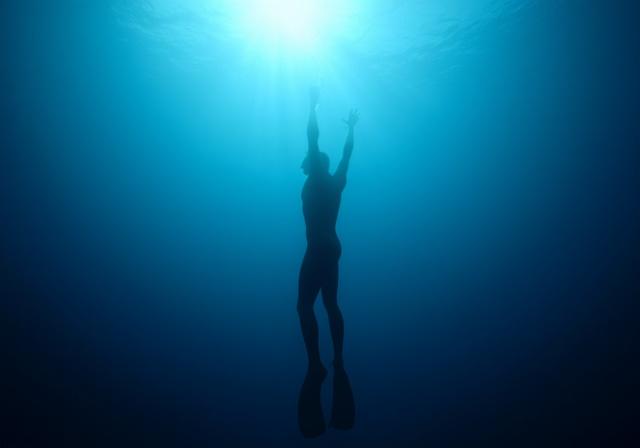 Freediver ascending from the blue depths